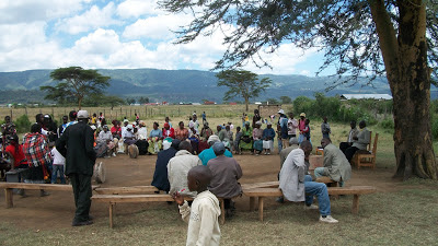 The people gathered under the tree to have church in an empty lot in the IDP camp.