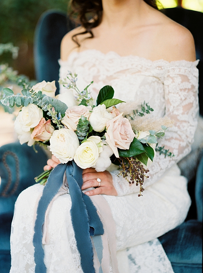 Stunning white and peach bouquet with greenery, berries, and blue ribbon | Photo by Dennis Roy Coronel | See more on thesocalbride.com