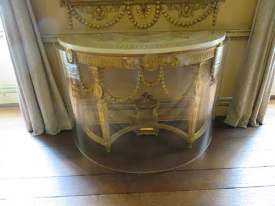 gilt demilune table protected by plastic