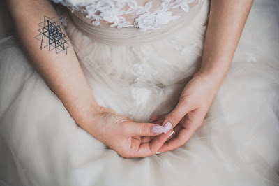 Close up on a bride's hands and white dress detail