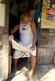 old man reading newspaper in his hut