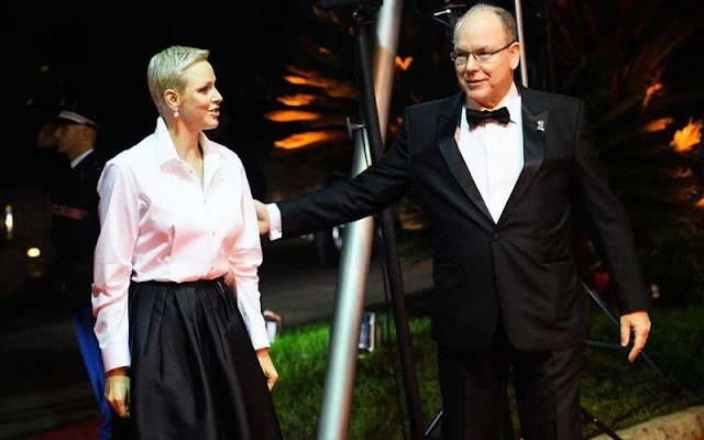 Princess Charlene wore a white silk shirt by Akris, and black pleated wide-leg skirt by Brunello Cucinelli. Dior pearl tribales earrings