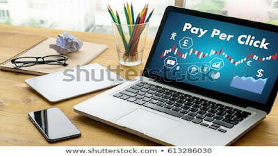 Small Business Online Presence ads work table with a computer displaying pay per click in its screen on the table with a smatphone, notepads, eye glasses and many coloured pencils in a holding glass cup on the table.