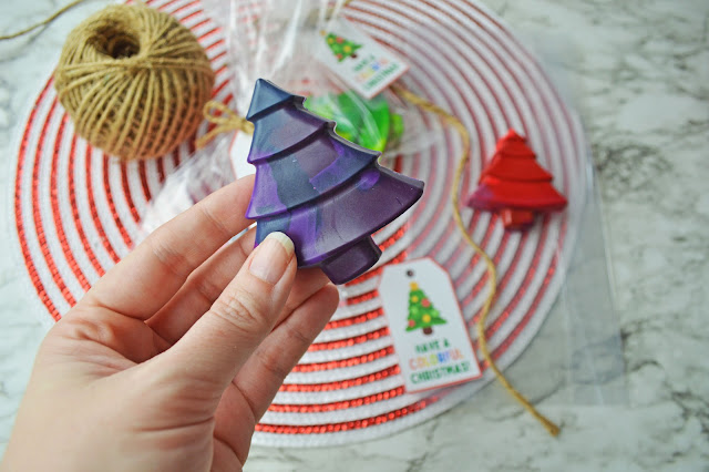 hand holding a purple christmas tree crayon.