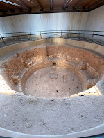 The archaeological remains of a large, circular room that is below ground level.