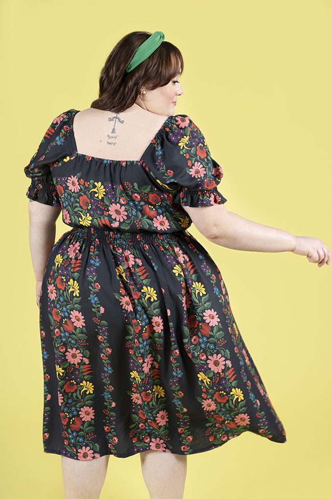 Plus size brunette woman from the back, wearing a navy floral dress with shirring on waist and sleeves