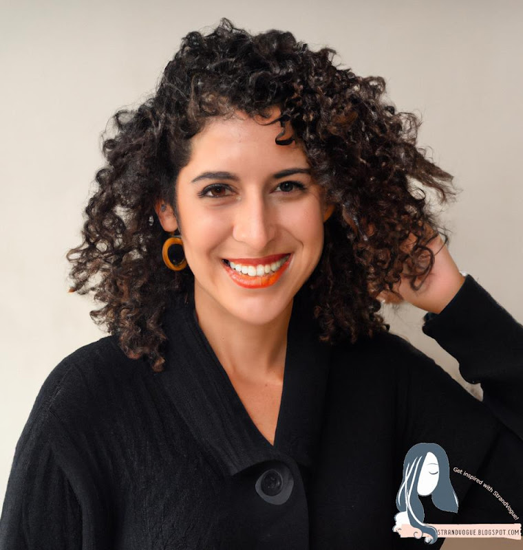 Image of a woman with curly shag, wearing a black sweater and smiling.
