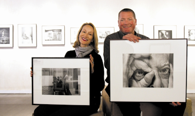 Sid and Michelle Monroe holding framed photographs inside Gallery