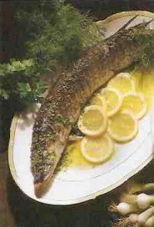 ryba na półmisku przystrojona gałązkami koperku, pietruszki i plasterkami cytryny