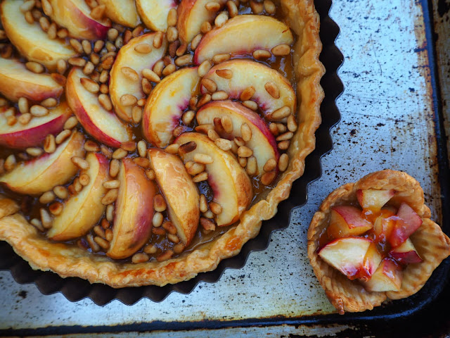 A large nectarine tart next to a small one on a baking tray