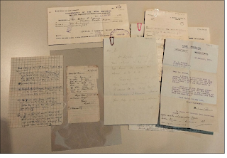 Shows seven paper documents that have a mix of handwritten and typewritten text on them.
