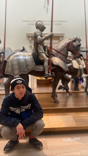 Mr. Juky Chen poses in front of a knight on horseback in the arms and armor wing of the Metropolitan Museum of Art.