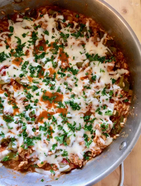 Pan of stuffed peppers skillet topped with cheese and parsley.