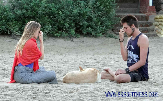 A couple doing Nadi Shodhana Pranayama on beach sand – Breathing exercise