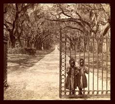 two slave girls standing behind bars of fully open gate