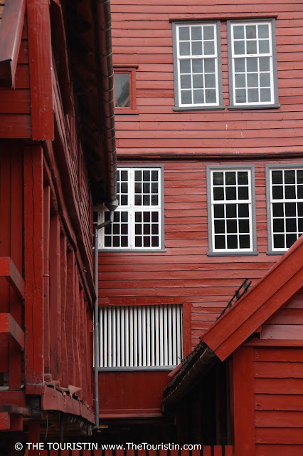 A several-storey tall wooden red cottage with white window frames.