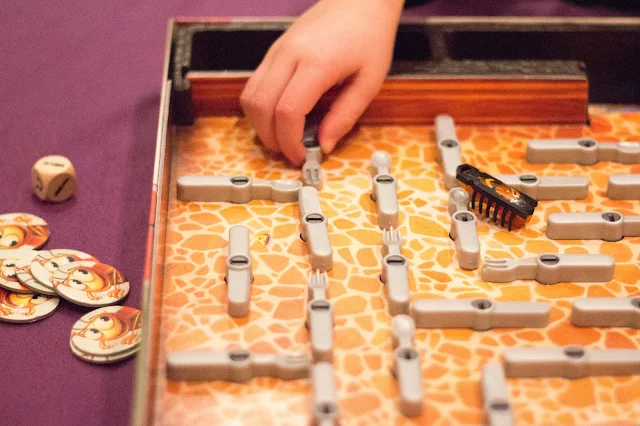 The Bugs In The Kitchen Board Game set up with a small hand about to turn a fork