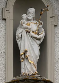 Der heilige Josef von Nazareth mit Lilie als Zeichen der Keuschheit hält das Jesuskind auf dem Arm. Jesus seinerseits hat den Reichsapfel bei sich. Die Statue findet sich am ehemaligen Kapuzinerkloster in Bremgarten.