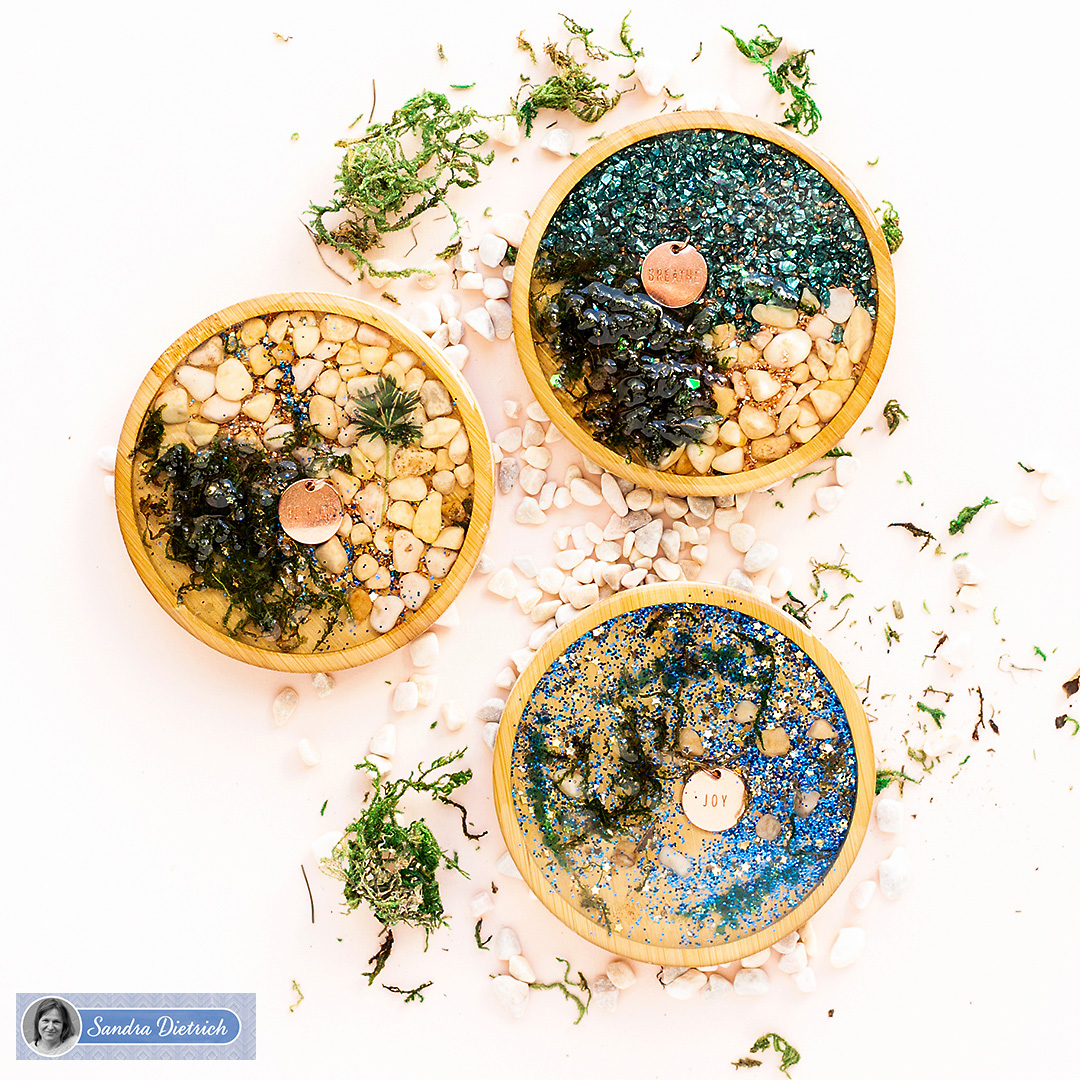 Handmade wood coasters with charms, white pebble stones, and green moss for shiny table decoration