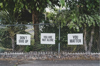 Signs on a gate saying “don't give up,”'you are not alone, and “you matter” as showing support for those addicted to different substances.