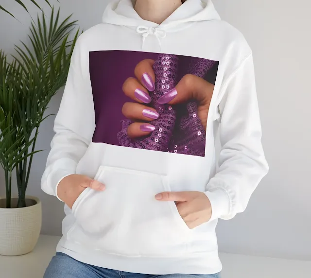 A Hoodie With Female Hand with Shiny Purple Nails is Holding Purple Glittered Fabric on Purple Background, Nail Care and Manicure Concept