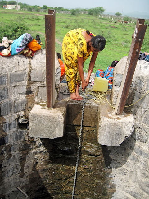 girl drawing water from well