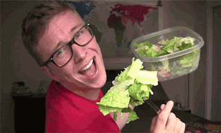 A man, with exaggerated facial expressions, poses whilst eating large mouthfuls of lettuce. He seems happy to be eating healthily.