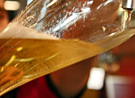 beer  being poured into a tall glass