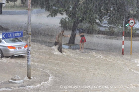 Un oficial de las Fuerzas Armadas Revolucionarias ayuda a una joven en la Calle J en el municipio Plaza de la Revolución, durante las lluvias caídas, en La Habana, Cuba,  el 29 de abril de 2015.