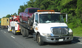 Image of tow truck with truck on bed being towed 