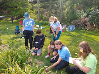 4-H volunteers and youth examining plants outdoors