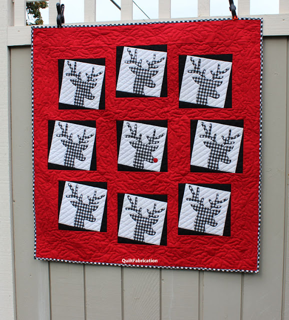 black and white checked deer heads in a circle with Rudolph in the middle all on a red background by QuiltFabrication