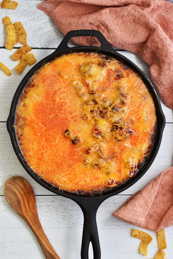 Melted cheese atop a chili mixture in a cast iron skillet, creating a luscious and gooey layer over the savory dish
