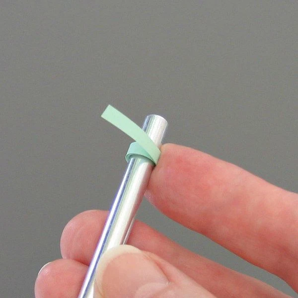 hand showing a rolled paper coil on small dowel, a paper piercer tool
