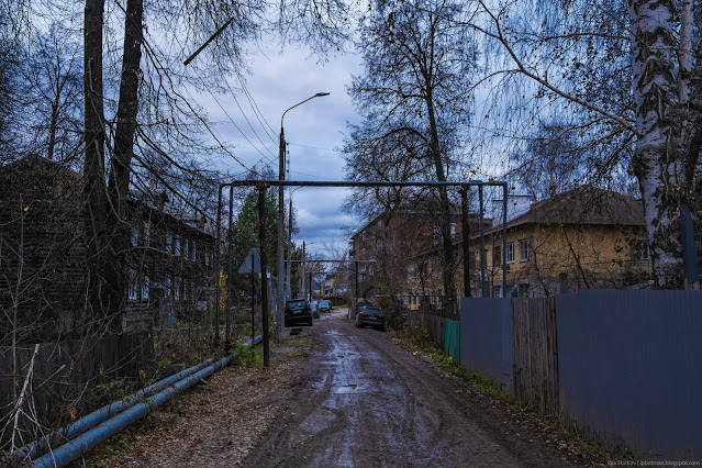 Узкая улица среди жилых зданий, покрытая грязью