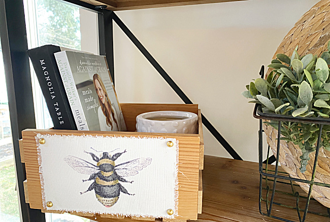wooden crate with bee on shelf with books