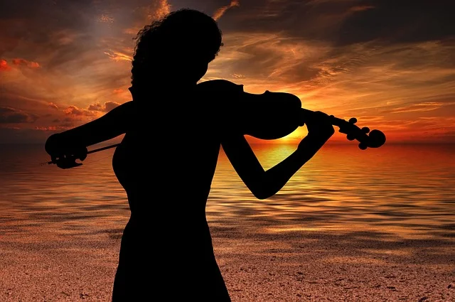 Silhueta de Mulher com um violino na praia ao amanhcer