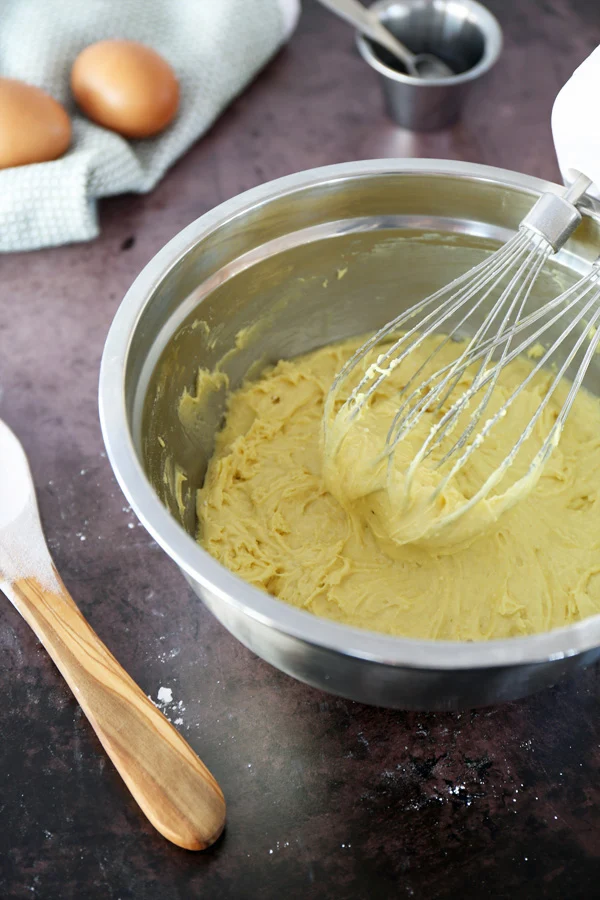 Stainless steel mixing bowl with batter for Lemon Cake Mix Cookies being mixed with a white hand mixer