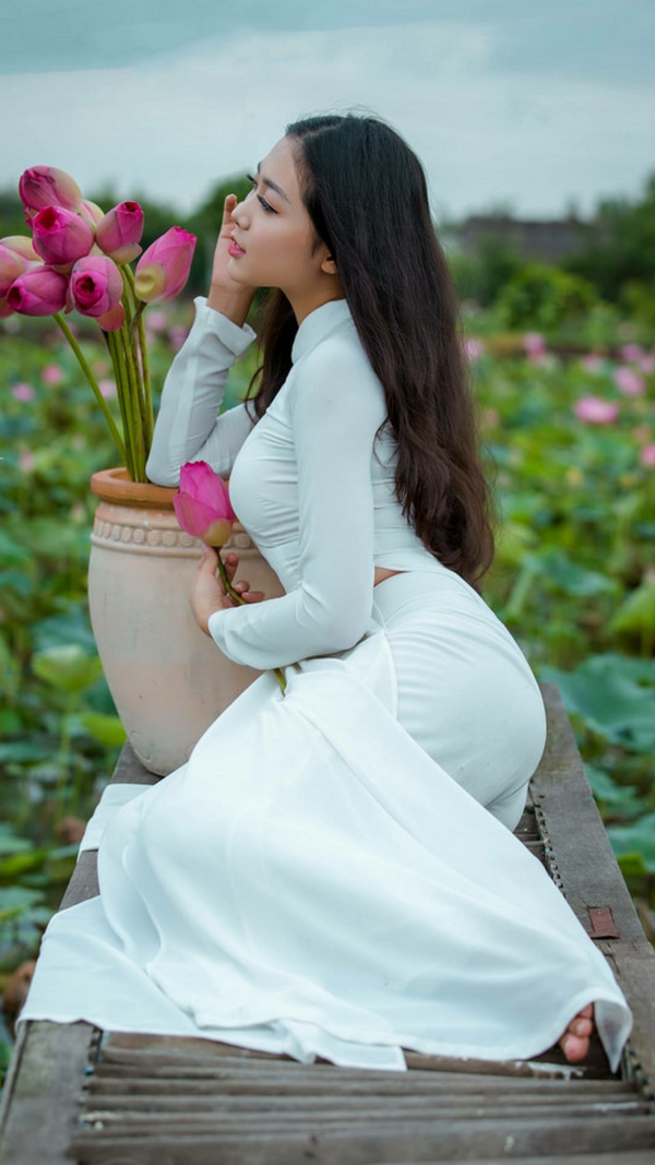 Thiếu nữ ngồi áo dài trắng, chậu hoa