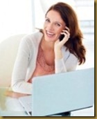 Portrait of a cheerful middle aged brunette using cellphone with laptop in front stock photography