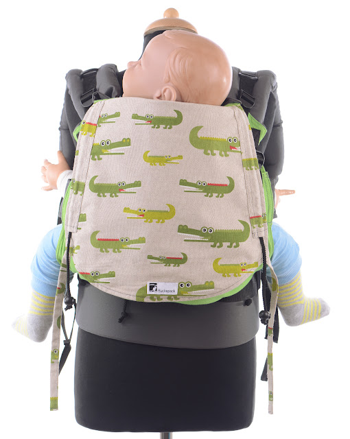 Ergonomische Babytrage aus grünem Tragetuchstoff, Krokodile auf der Kopfstütze.