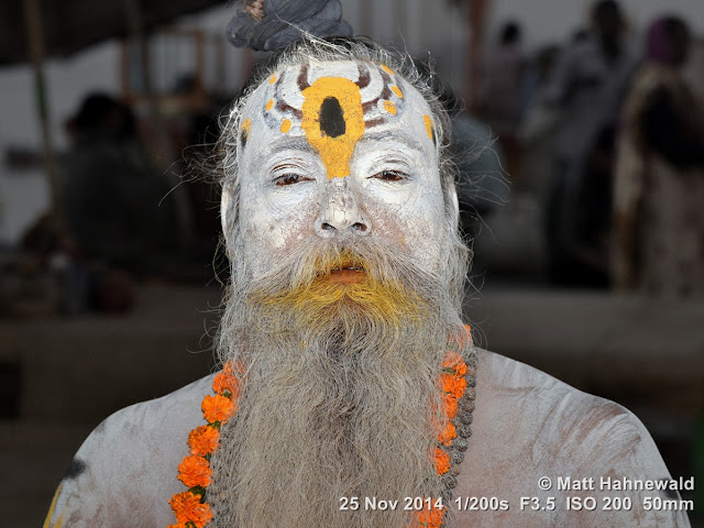 Matt Hahnewald; Facing the World; closeup; street portrait; headshot; outdoor; India; Cow Belt; Varanasi; Benares; Uttar Pradesh; Ganges River; ghat; Hinduism; holy; tradition; culture; world cultures; worship; sadhu; Indian man; colour; photography; religion; face; eyes; eye contact; hair; beard; devotee; temple; holy man; vibhuti; white ash; marigold garland; mala; tilaka; nightshot; flash; flash fired; body covered with sacred white ash