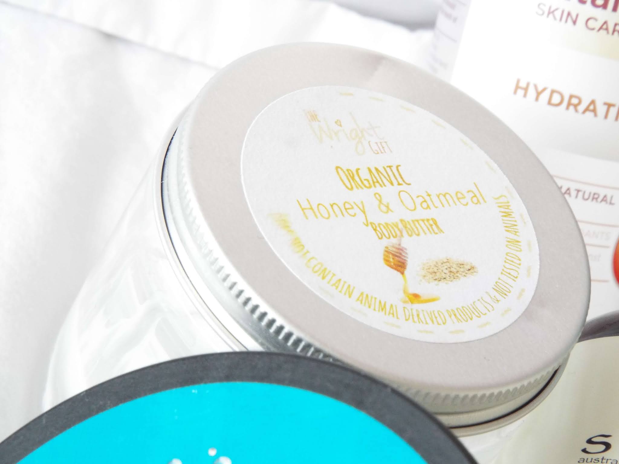 The Wright Gift Organic Honey & Oatmeal Body Butter, in clear plastic tub, with tin lid and label with honey and oats pictures.