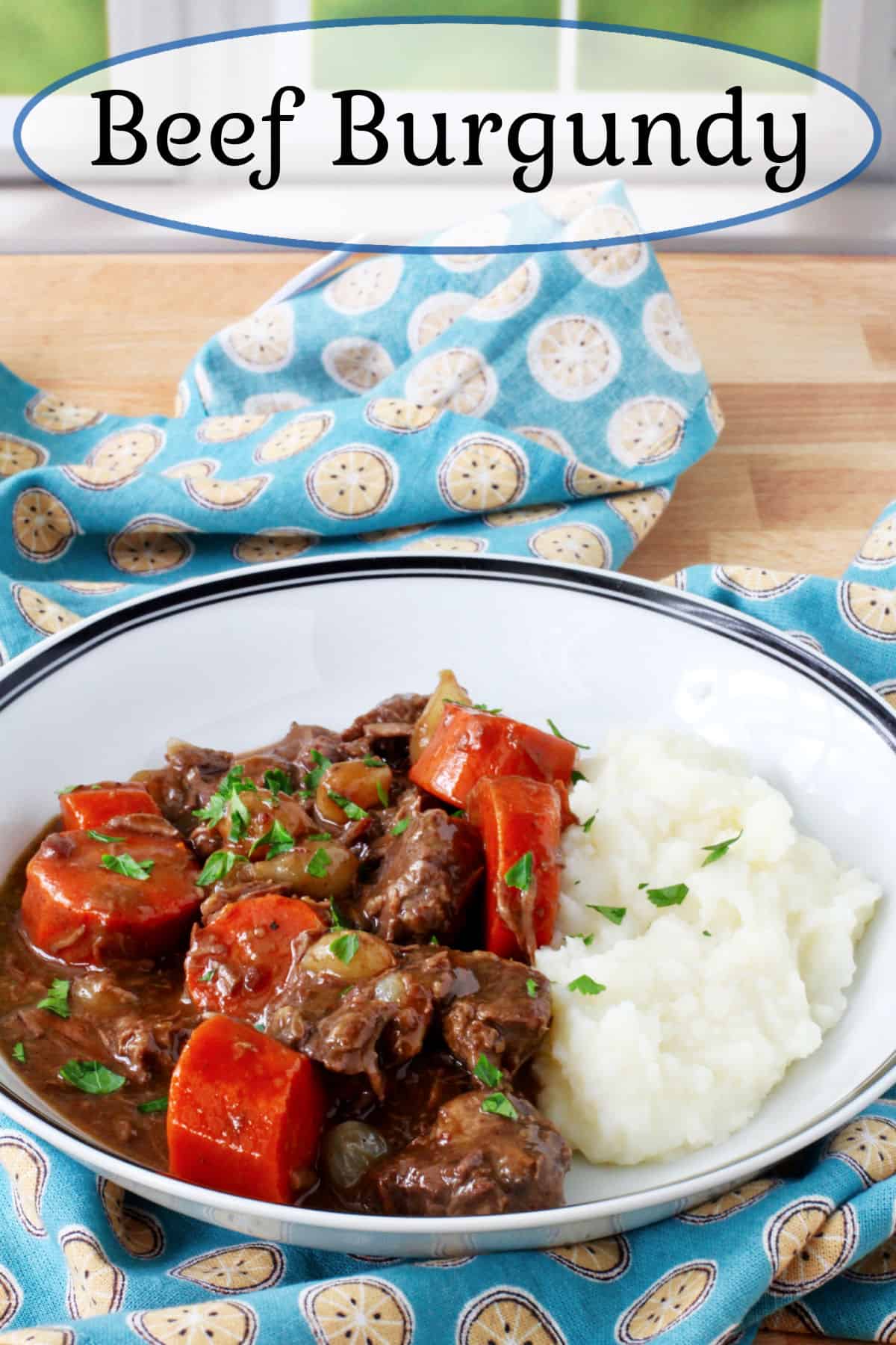 Beef Burgundy in a blue rimmed bowl over mashed potatoe.