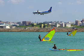 plane landing over windsurfers