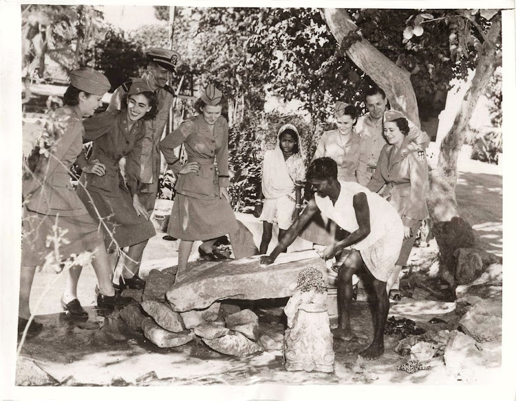 A Dhobi (Laundryman) is washing Clothes on a Stone slab and Five U.S. Army Nurses are Watching - India, 1943