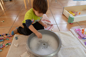 Child washing toys in a bowl