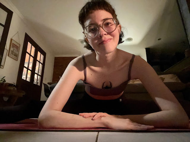 Foto da minha pessoa com os antebraços no chão, olhando para a câmera e as pernas alongadas em espacate num tapete de yoga