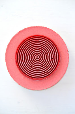 Die Torte entsteht: Foto von oben auf die Torte – zu sehen ist das rosarote Dirndlmousse, darauf die Himbeerspirale.