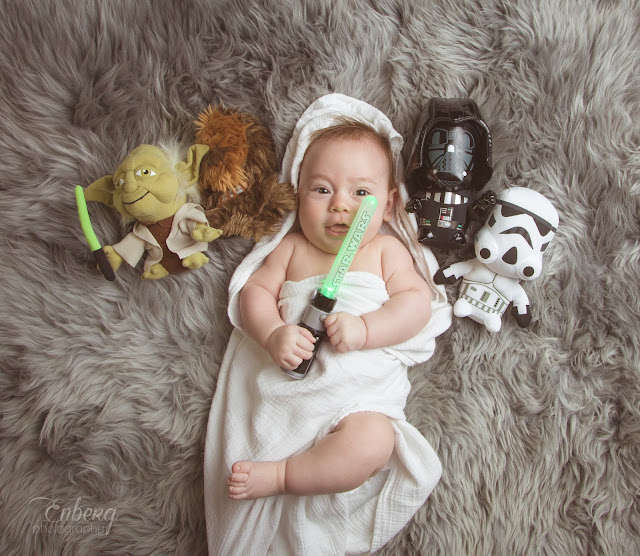 newborn baby boy photographed by Enberg Photography as a Star Wars Jedi with light saber on grey fur rug